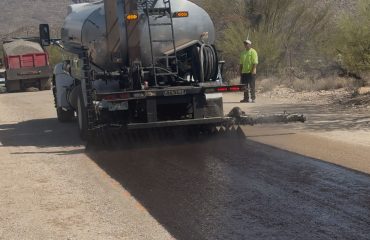 A truck from APS Chip Sealing & Asphalt Paving spreading asphalt layer as part of the process of driveway paving in Tucson
