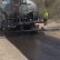 A truck from APS Chip Sealing & Asphalt Paving spreading asphalt layer as part of the process of driveway paving in Tucson