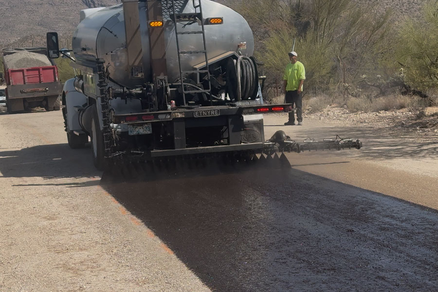A truck from APS Chip Sealing & Asphalt Paving spreading asphalt layer as part of the process of driveway paving in Tucson